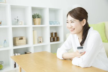 Mutlu Asyalı kadın evde televizyon izliyor.