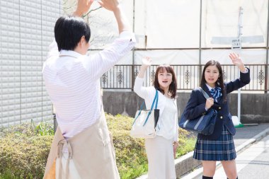 Asyalı bir adam karısına ve kızına veda ediyor.