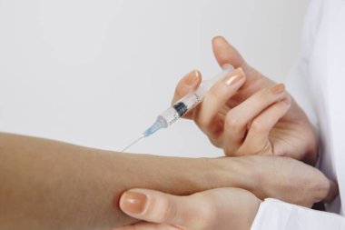 Doktor hastaların eline iğne yapıyor. 