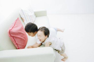 Kanepede oynayan Asyalı küçük çocuk ve kız.