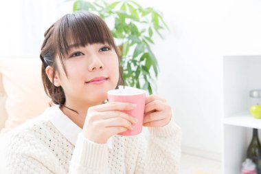 Güzel genç bayan evde çay içiyor.