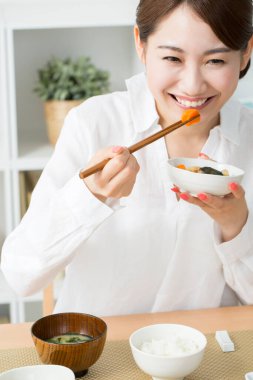 Genç Japon kadın çubuklarla yemek yiyor.