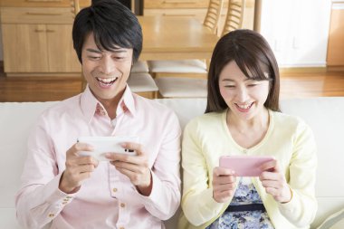 Genç Asyalı çift akıllı telefon kullanıyor.