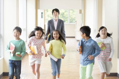 Öğretmenli bir grup Japon çocuk okul koridorunda yürüyor. 