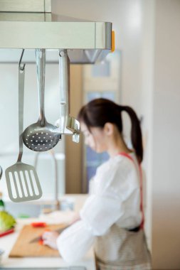 Asyalı kadın aşçı mutfakta yemek yapıyor.