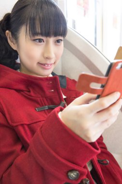 Genç Asyalı kadın cep telefonuyla naklediliyor. 