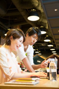 Genç çift ofiste dizüstü bilgisayar kullanıyor. 