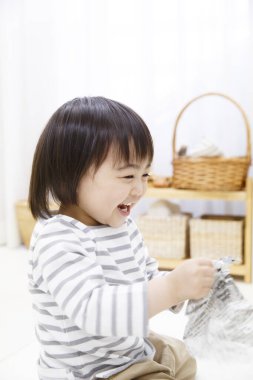 Tatlı Asyalı çocuk gazeteyle oynuyor. 