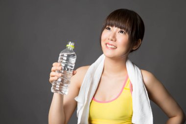 Spor salonunda elinde bir şişe su tutan Asyalı kadın.