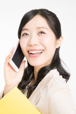 Akıllı telefonlu güzel Japon iş kadını beyaz arka planda gülümsüyor. 