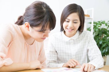 İki genç Asyalı kadın evde okuyor..