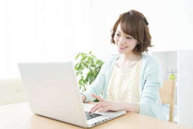 Genç Asyalı kadın dizüstü bilgisayarla çalışıyor.