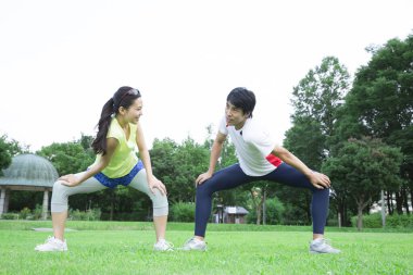 Sportif genç Asyalı çift parkta koşmadan önce geriniyor.