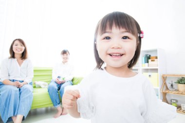 Ailesiyle birlikte beyaz gömlekli, gülümseyen kız.