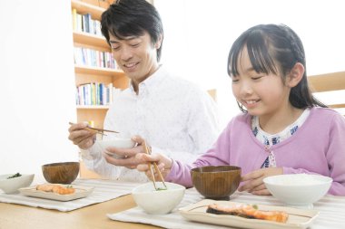 Asyalı Japon ailesi kahvaltısını evde yapıyor.