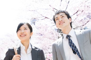 Şehir caddesinde kiraz çiçekleri olan iki Japon iş adamı.