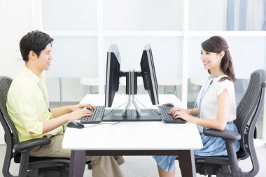 Genç Asyalı iş çifti ofiste bilgisayar üzerinde çalışıyor.