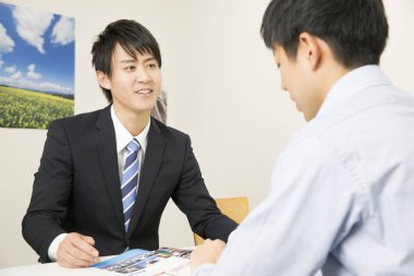 Asyalı işadamı ofiste bir müşteriyle çalışıyor.