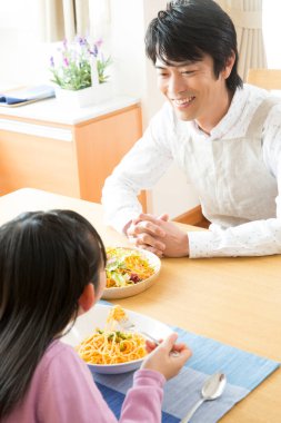 Genç baba ve kız mutfakta makarna yiyorlar.