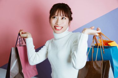 Alışveriş torbaları tutan genç Asyalı güzel bir kadın, stüdyo fotoğrafı. 