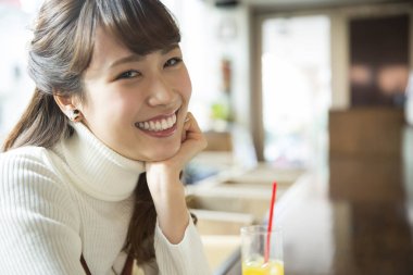 Restoranda portakal suyu içen Asyalı kadın.