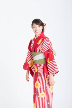 Beyaz stüdyo arka planında poz veren geleneksel kırmızı kimonolu güzel Asyalı kadın portresi.