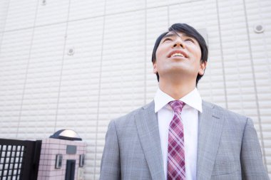 Takım elbiseli genç Japon işadamı evden ayrılıyor.