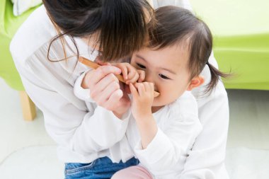 Evdeki oturma odasında genç annesiyle oynayan tatlı bir Japon kızı.