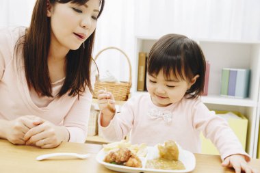 Annesi evde Japon yemeği yiyen tatlı Asyalı kız.