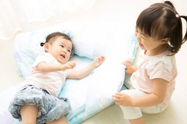 İki küçük çocuk yumuşak yatakta oynuyorlar.