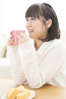 Güzel genç bayan evde çay içiyor.