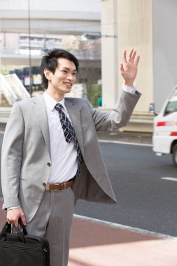 Genç Japon iş adamının yakın plan portresi. Şehir sokaklarında el sallıyor.