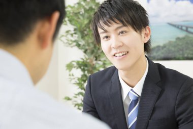 Asyalı işadamı ofiste bir müşteriyle çalışıyor.