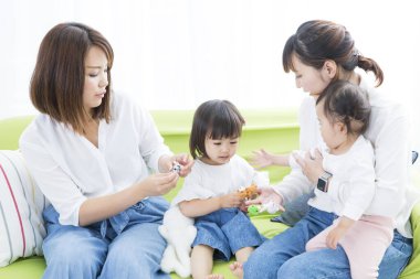 Anneler ve sevimli Çinli çocuklar evde oyuncaklarla oynuyorlar.