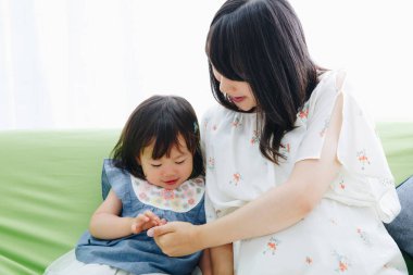 Evdeki oturma odasında annesiyle oynayan tatlı Asyalı küçük kız.