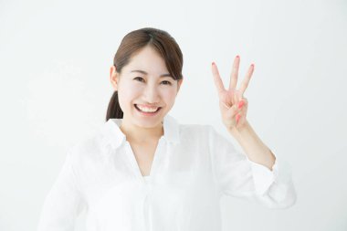 Beyaz arka planda üç parmağını gösteren güzel bir Japon kadın. 