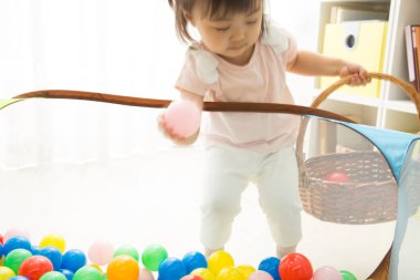 Evde plastik toplarla oynayan Asyalı küçük kız. 