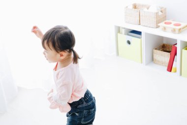 Küçük Asyalı kız yerde duruyor. 