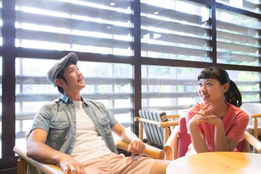 Kafede düzen bekleyen Asyalı bir çift var. 