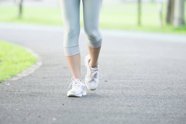 Yolda kadın bacaklarının spor ayakkabılı alt kısmı..