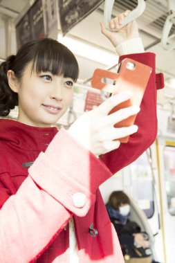 Trende akıllı telefon kullanan genç bir Japon kadın. 