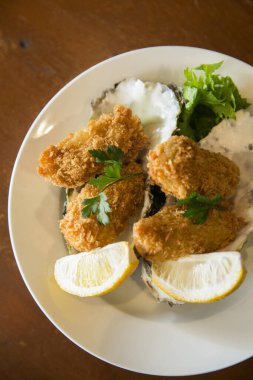 Limon ve maydanozla süslenmiş kızarmış istiridye.