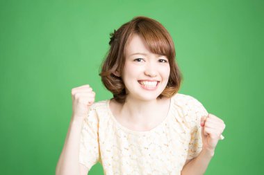 Yeşil arka planda yumruklarını gösteren güzel Japon kadının portresi. 