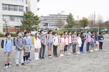 Okul bahçesinde dikilen bir grup Japon çocuk. 