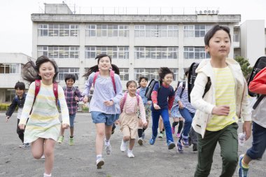 Bir grup neşeli okul çocuğu dersten sonra eve koşuyor..