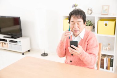 Usta Asyalı adam cep telefonu ve akıllı telefon kullanıyor. 