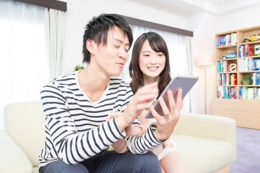 Mutlu Asyalı çift evde tablet kullanıyor.
