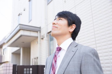 Takım elbiseli genç Japon işadamı evden ayrılıyor.