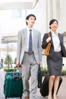 Şehir caddesinde bavulla yürüyen iş adamları.