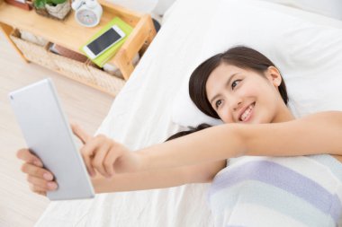 Genç Asyalı kadın tablet bilgisayarla fotoğraf çekiyor. 